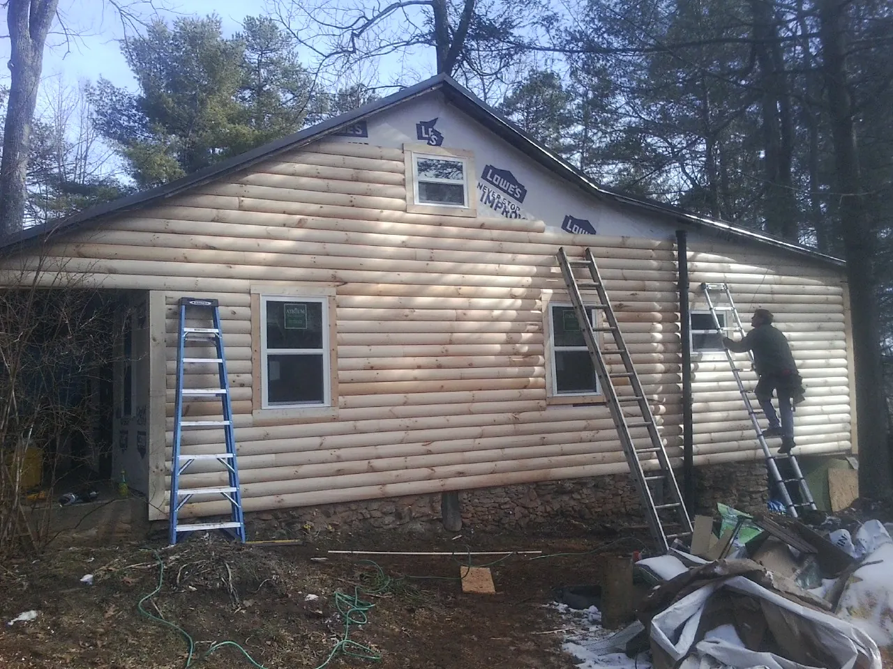 Ladders set against fresh log siding during an exterior remodel in Rushville